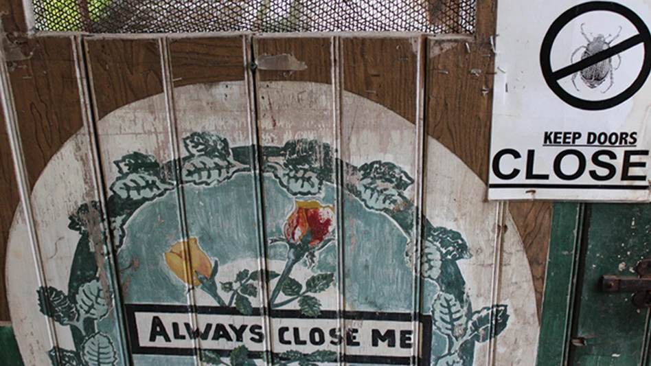 A wooden door with a painted white and blue circle of flowers, with black text that reads Always Close Me. A white paper sign stapled to the door says Keep Doors Close, with a bug in the center of a no symbol.